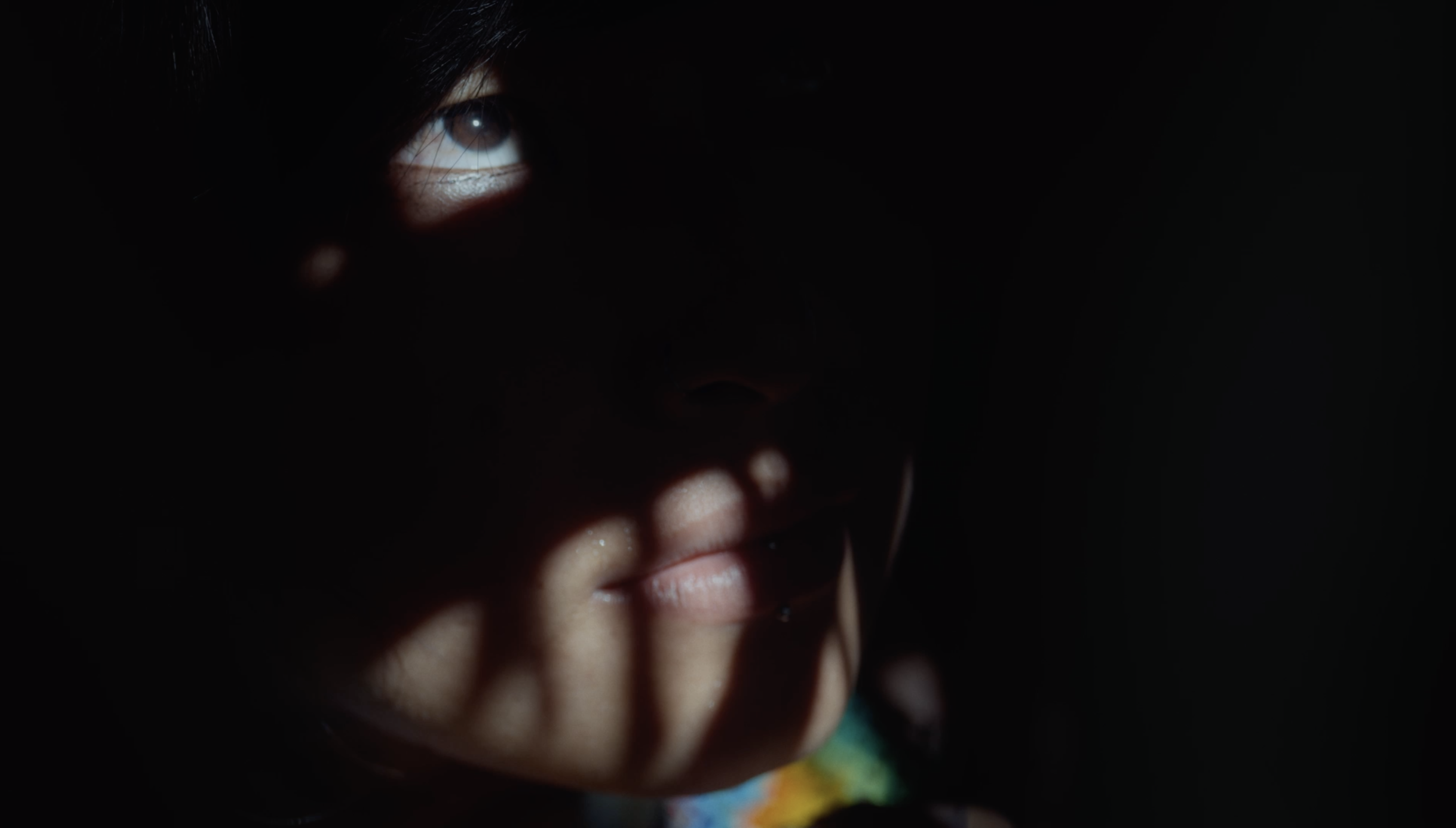 A child's face in shadow, one eye catching the light